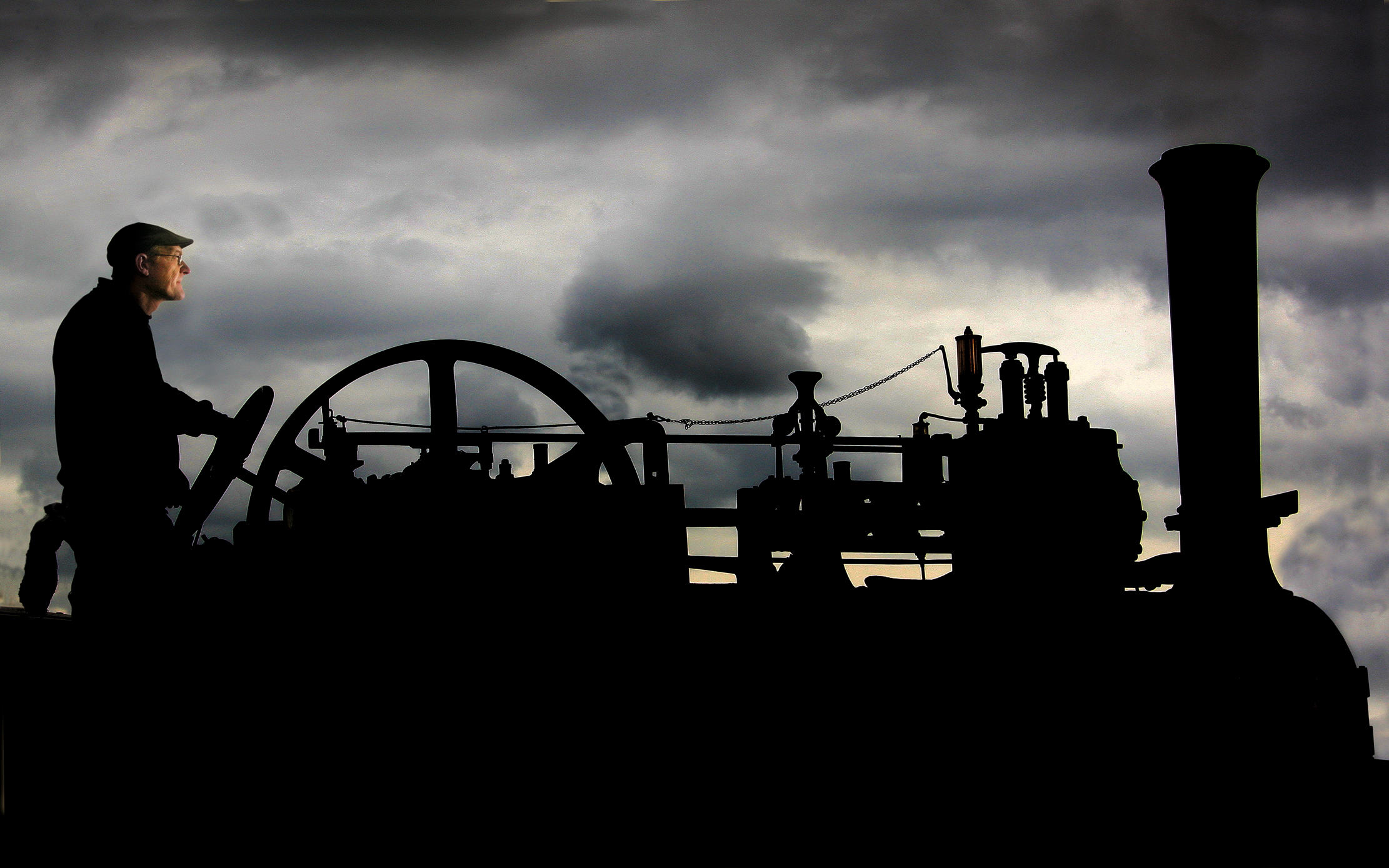 A traction engine and its operator silhouetted against the sky