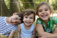 Three young siblings smiling at the camera