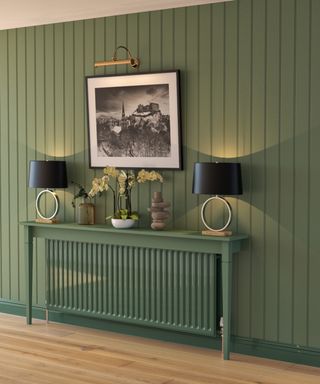 green tongue and groove wall panelling in hallway with shelf and radiator painted in same shade of green