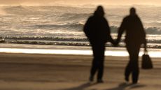 Couple walking on beach in silhouette