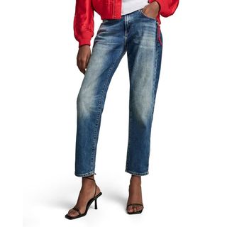 Woman modelling Mom jeans with strappy heels and a red jacket 