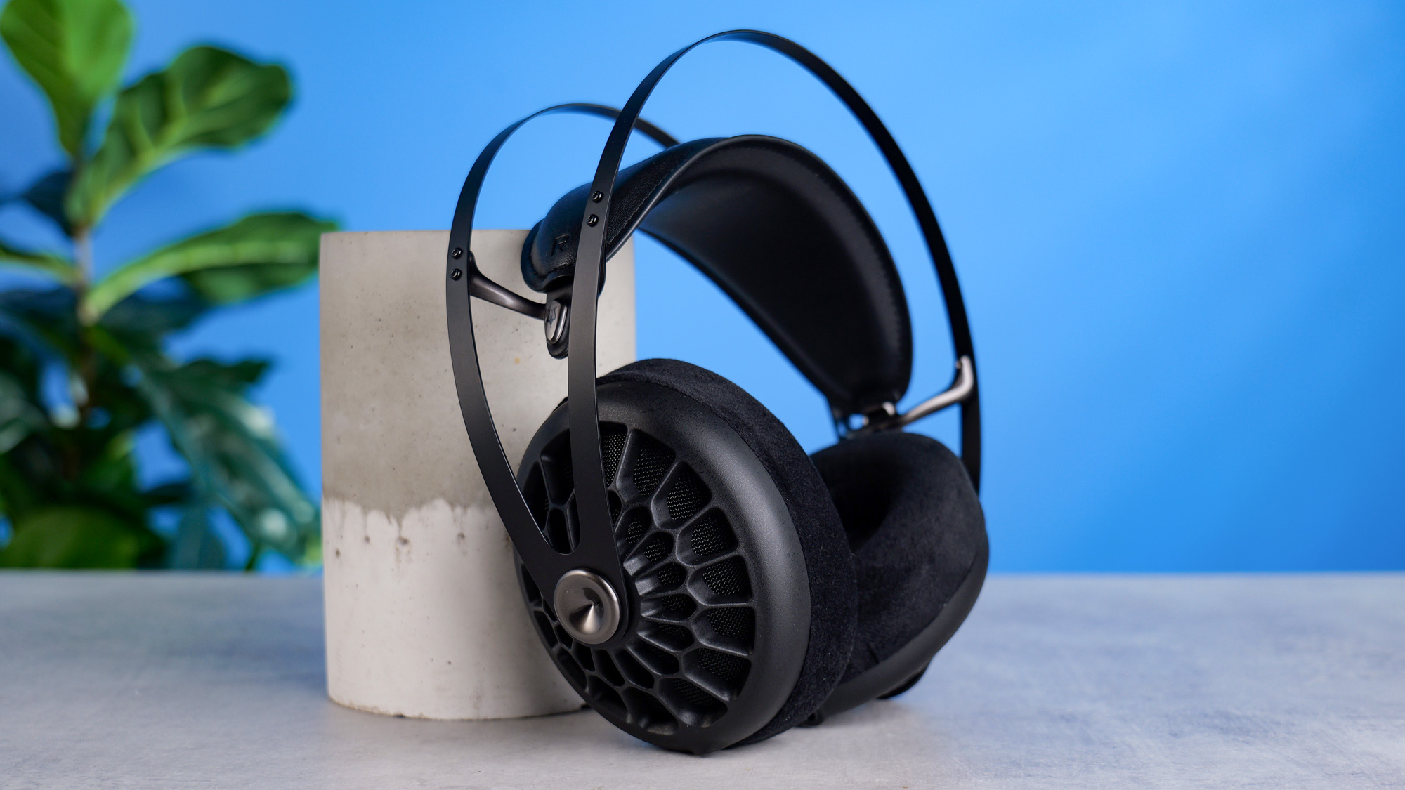 The Meze 105 AER propped up on a stone plinth against a blue background
