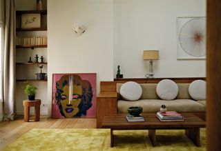 A living room with lime green carpet, and wooden sofa and artworks