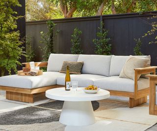 teak and upholstered outdoor chaise sofa on a patio