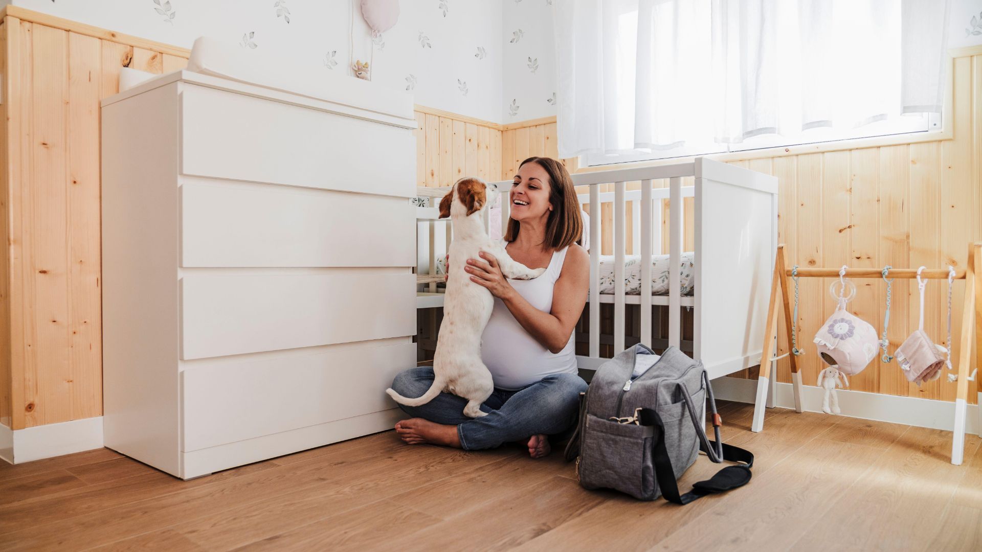 Pregnant woman cuddling dog in nursery