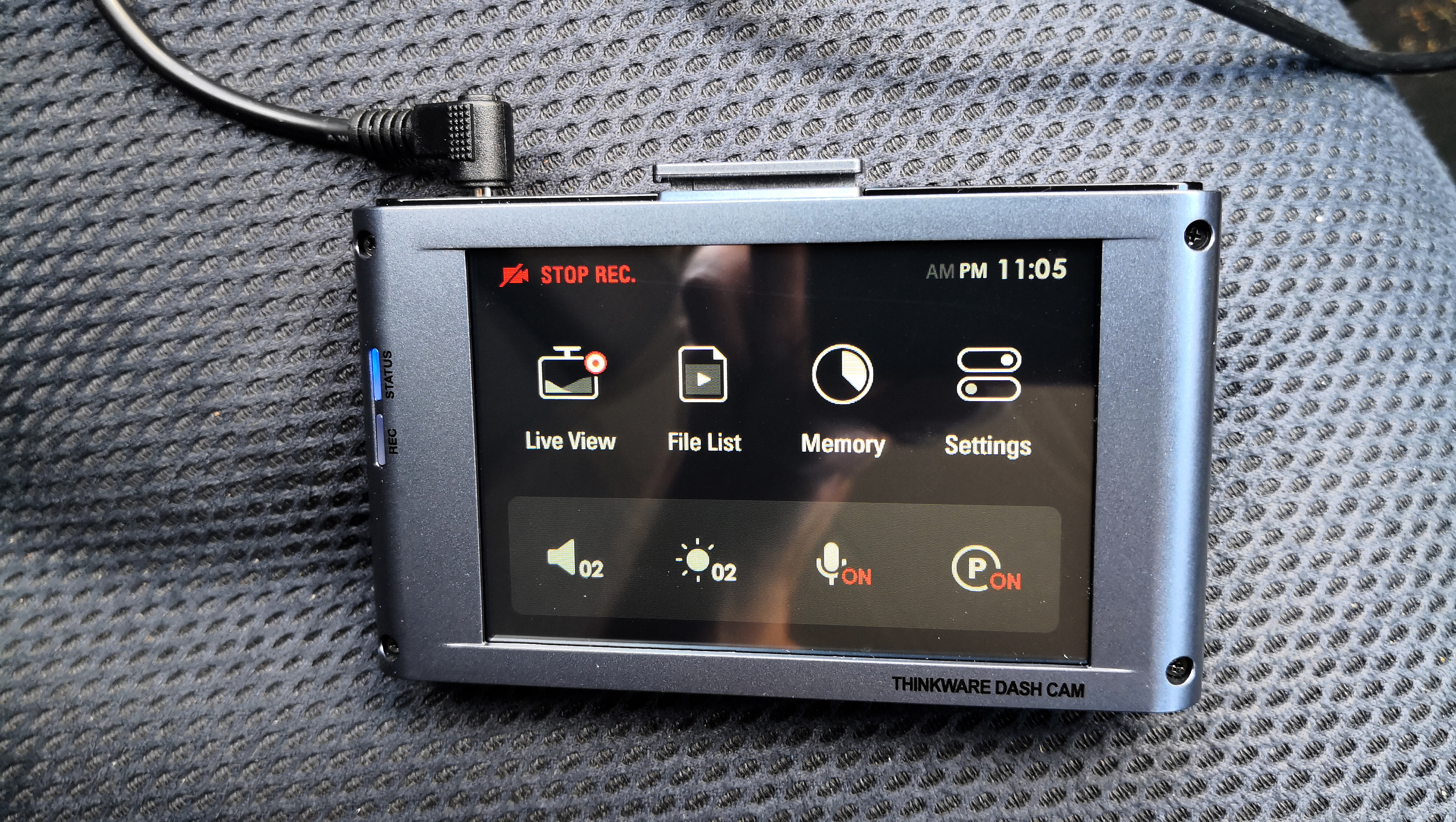 The Thinkware X1000 dash cam sitting on a car seat