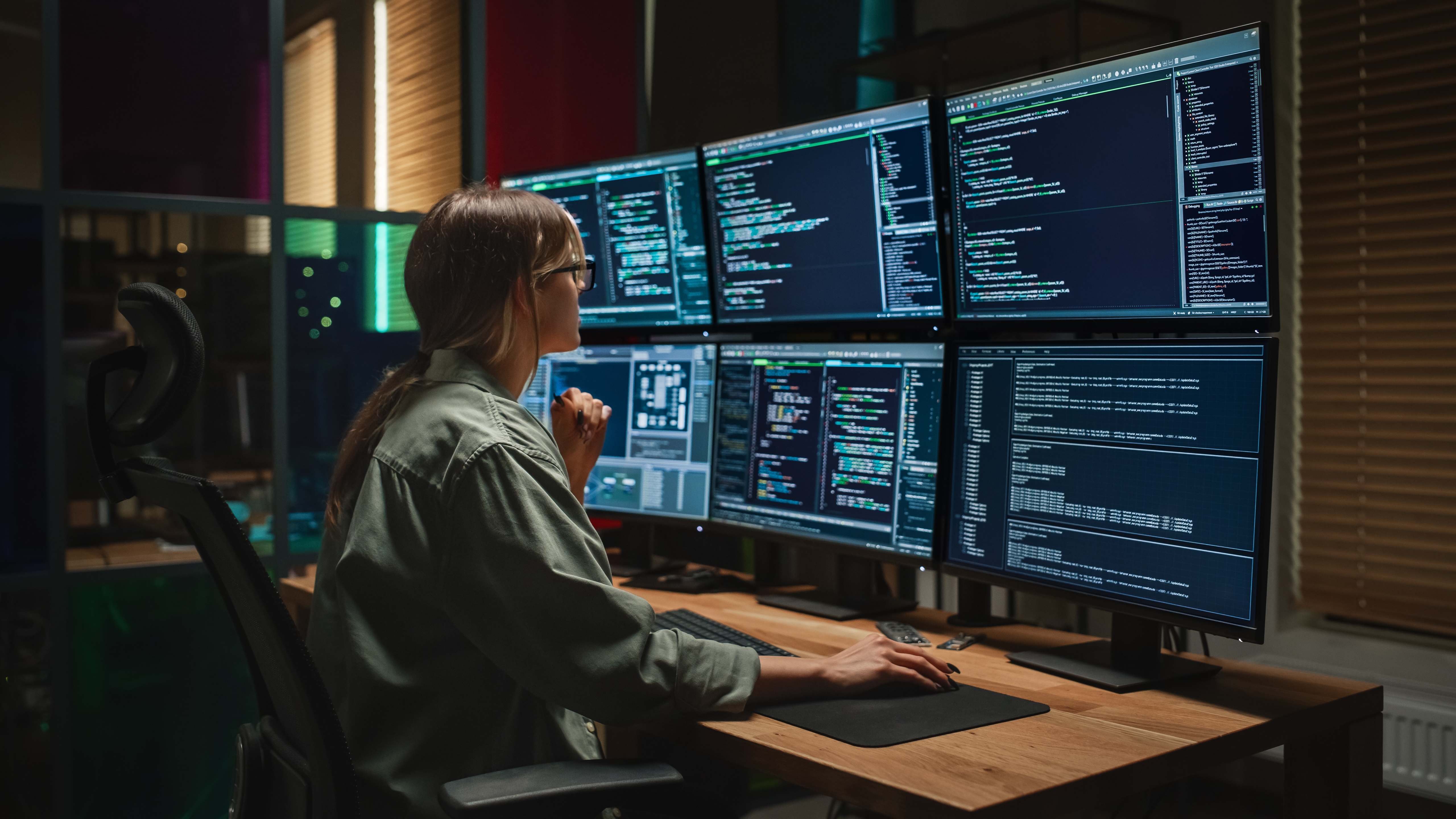 Female Programmer Coding on Desktop Computer With Six Displays in Dark Office