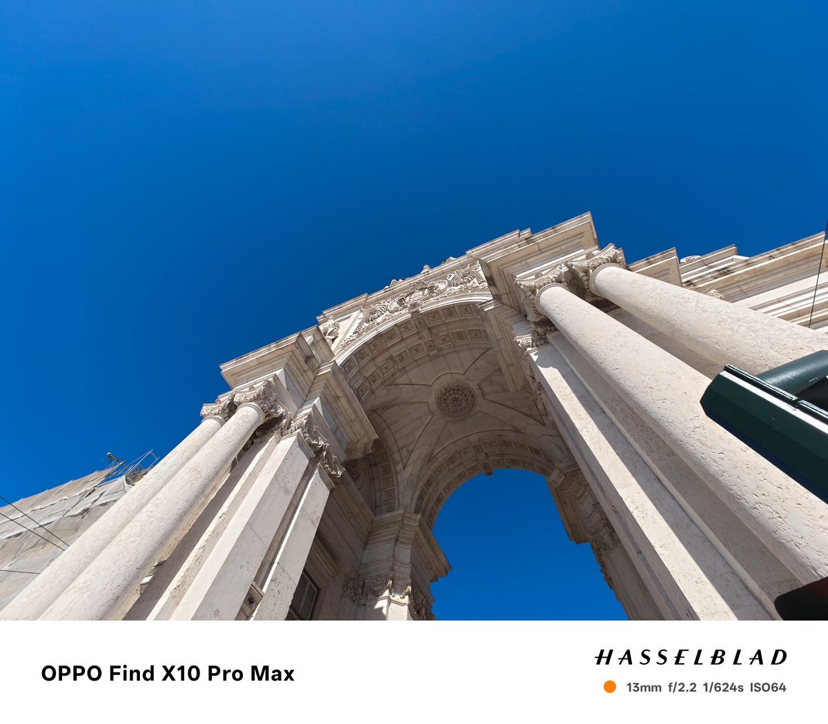 Dramatic low-angle view looking up through an ornate white stone arch against blue sky.