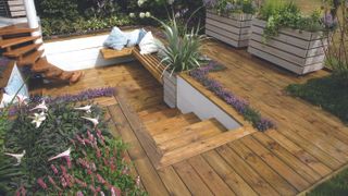 sunken seating area in garden with wooden decking and spiral stairs
