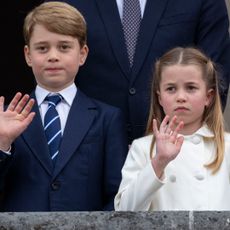 Prince George wears a navy suit with a striped tie, Princess Charlotte wears a white coat, and Prince Louis looks bored