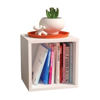 A white cube storage bookcase with books inside and decor on top