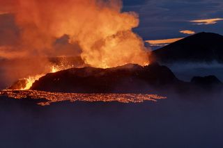 volcano erupting in Iceland with lava flowing from a crater