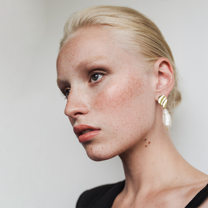 a model with blonde hair tied up looking off to the right hand side