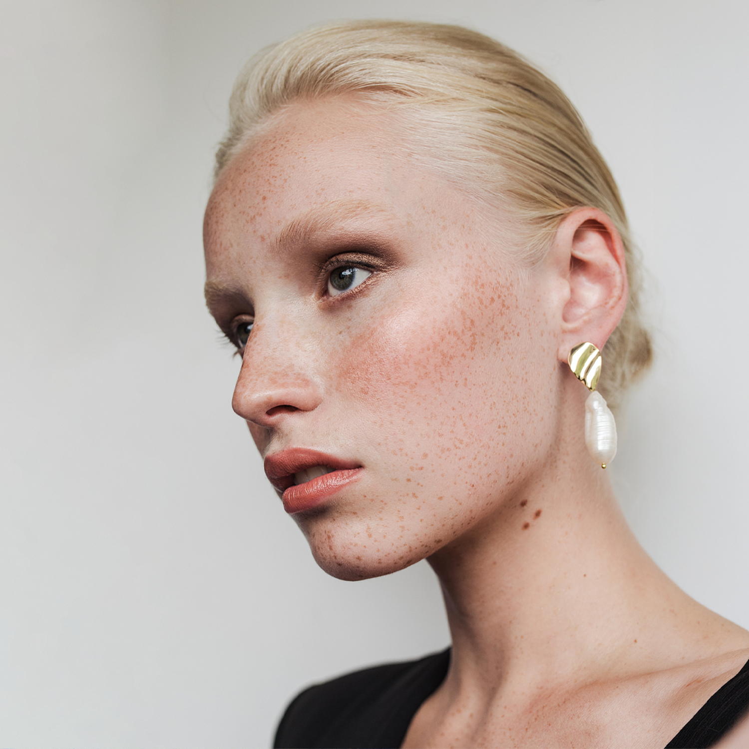 a model with blonde hair tied up looking off to the right hand side