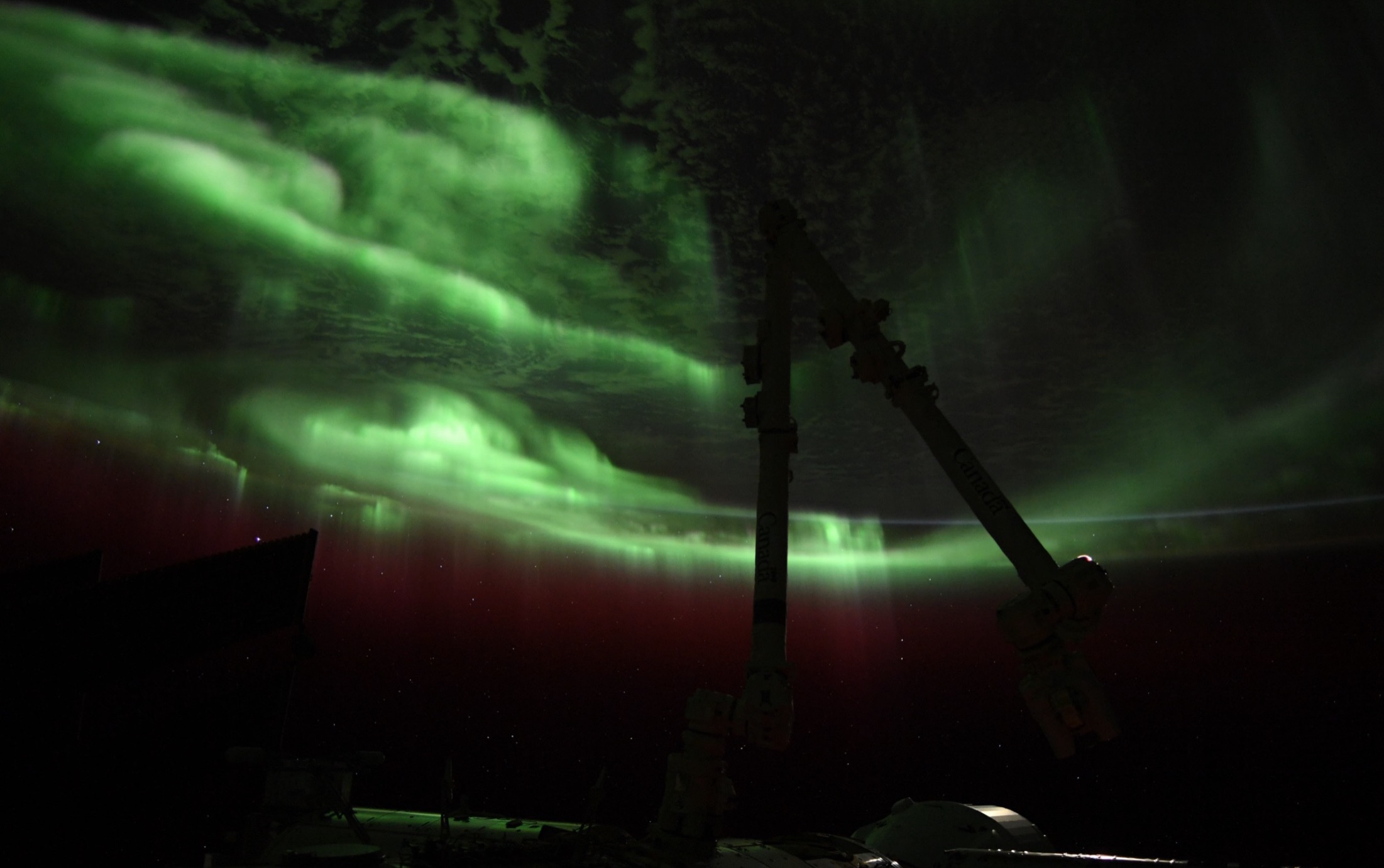 green auroras with an international space station structure in shadow, in the foreground