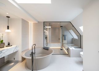 A white bathroom with elements of black scattered around it. In the bathroom is a large bathtub as well as a shower with a large internal window.