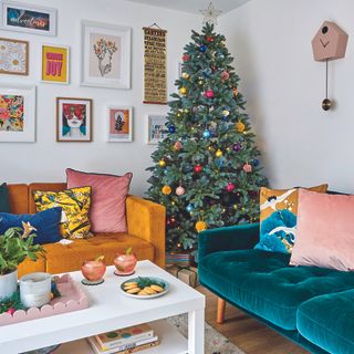 Christmas tree with colourful baubles in living room with coloured sofas