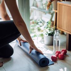 Strength training at home: A woman rolling out her workout mat