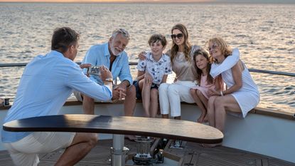 Man taking photo of happy multi-generational family on yacht with a smartphone