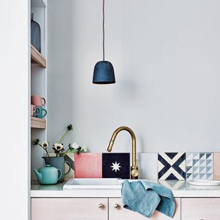 Kitchen sink surrounded by tiles and accessories in muted pastel shades