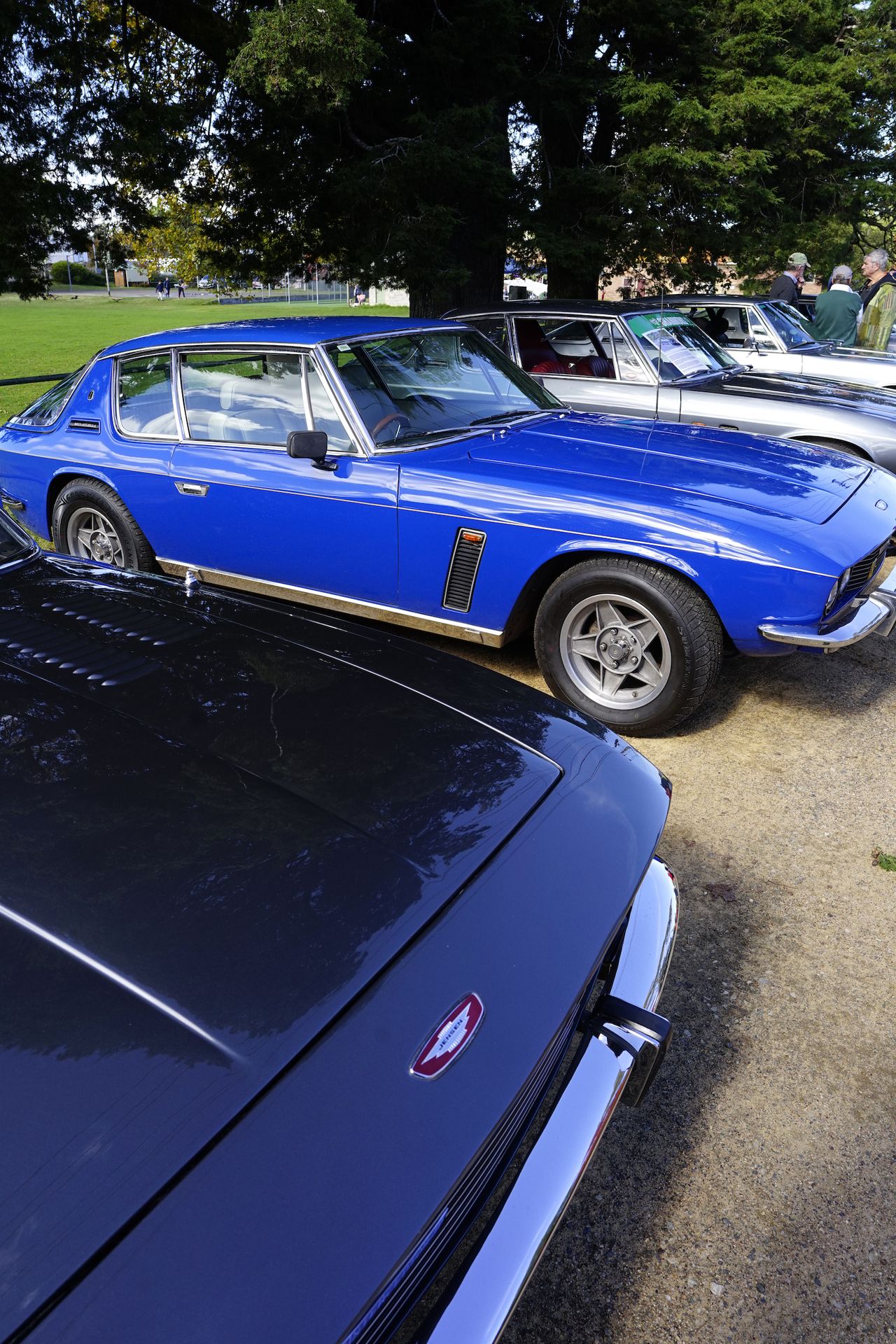 A blue classic car parked beside others