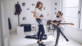 Man and woman play guitar together