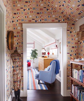 landing with nautical flag wallpaper view to bedroom with striped rug and blue armchair