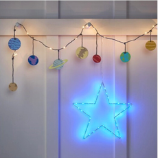 The Planet Fairy Lights (£12.99) and Blue Osby Starlight (£22.99) hanging on white wall