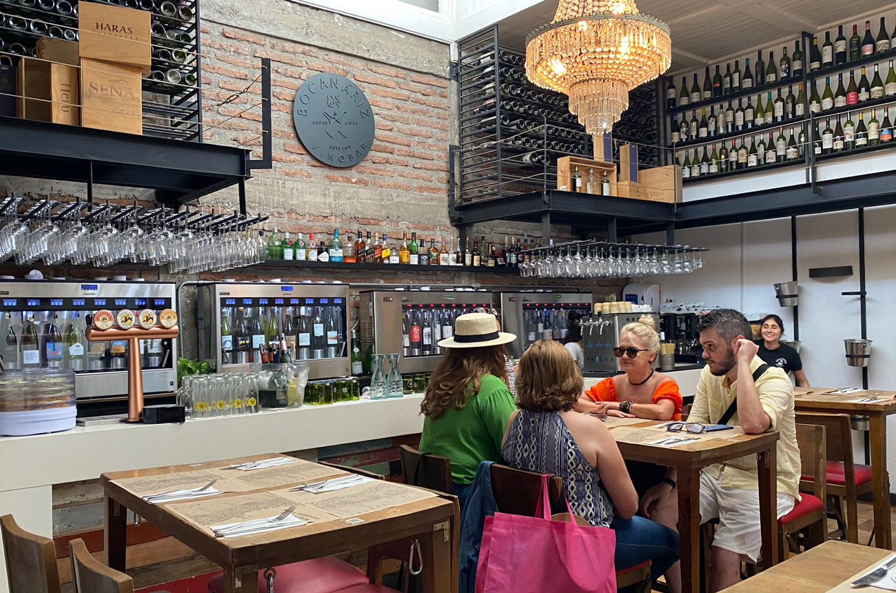 People sitting at a high table in a bar with bottles in the background