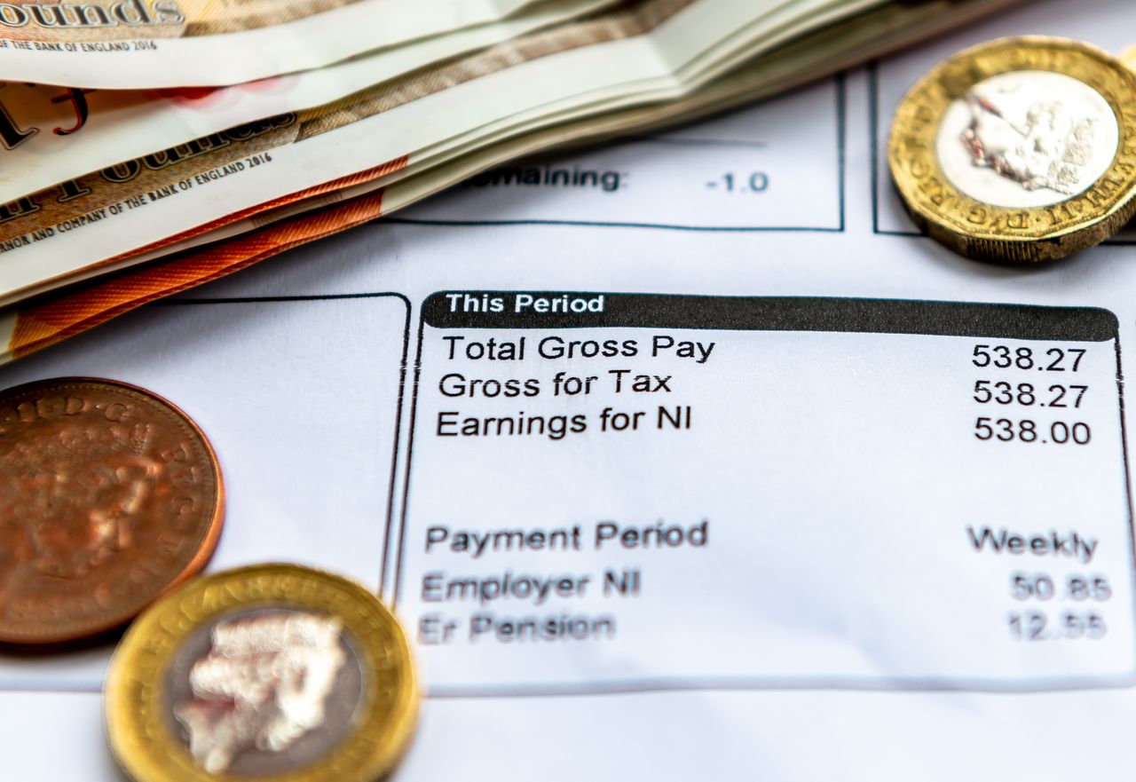 A payslip with some bank notes and coins.