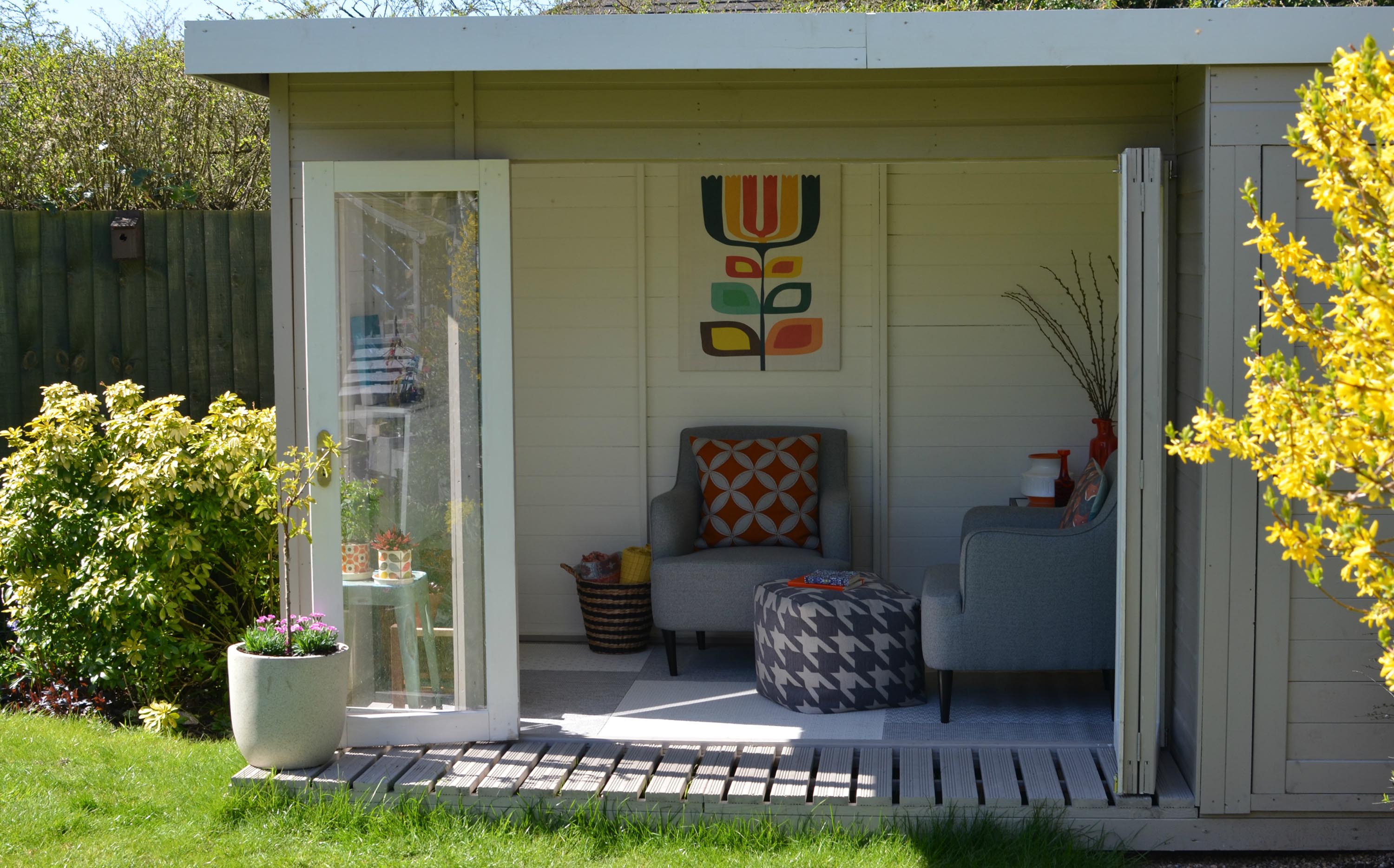 Summerhouse on a deck with wall art grey armchair and footstool