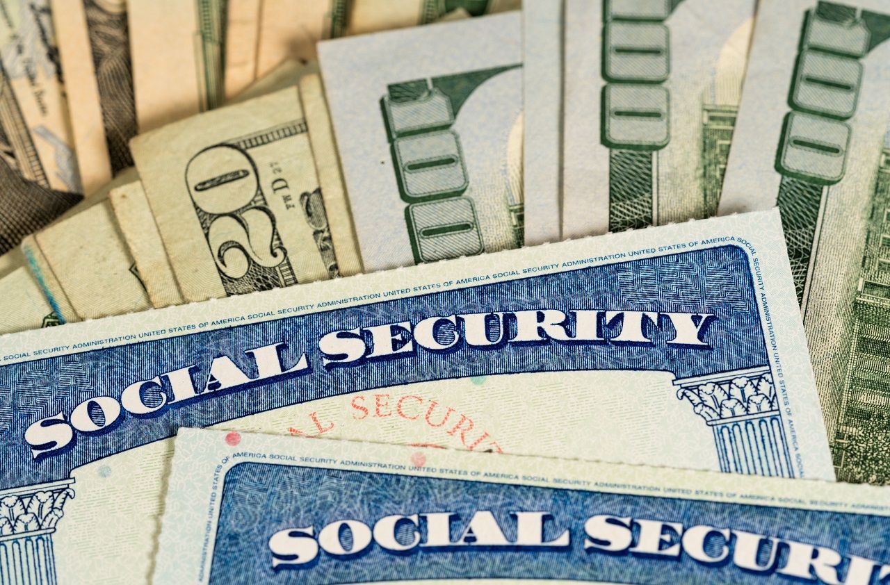 USA Social security cards laid on pile of dollar bills to illustrate money in retirement