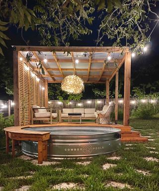 stock tank pool by Cowboy Pools with festoon lights and garden structure