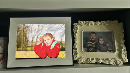 Aura Aspen digital photo frame on bookshelf with regular framed photographs