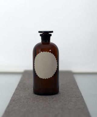 An empty amber glass bottle with plain grey sticker