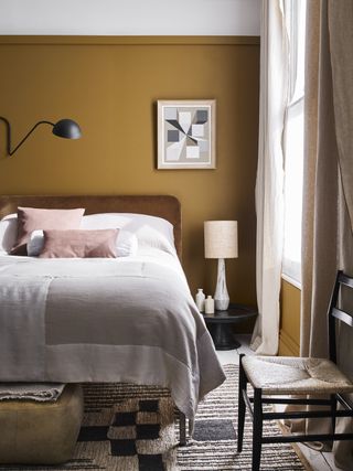 A mustard orange bedroom with neutral bed covers