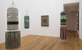 A series of intricately beaded punching bags refer to the cathartic nature of boxing