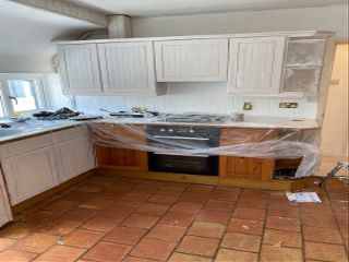 Becky Lane's kitchen wrapped up in protective plastic, while half is being painted white and the other half is still orange pine