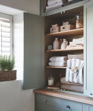 Utility room ideas for storage with an organised wooden cupboard full of laundry things.