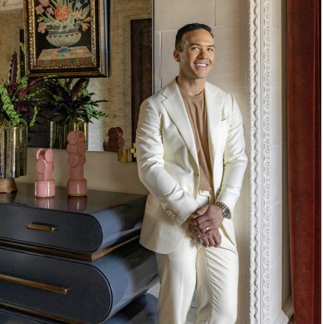 man in cream suit standing and smiling to camera