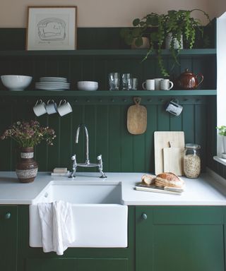 Dark green and white kitchen with white sink and countertops, open shelving, shiplap
