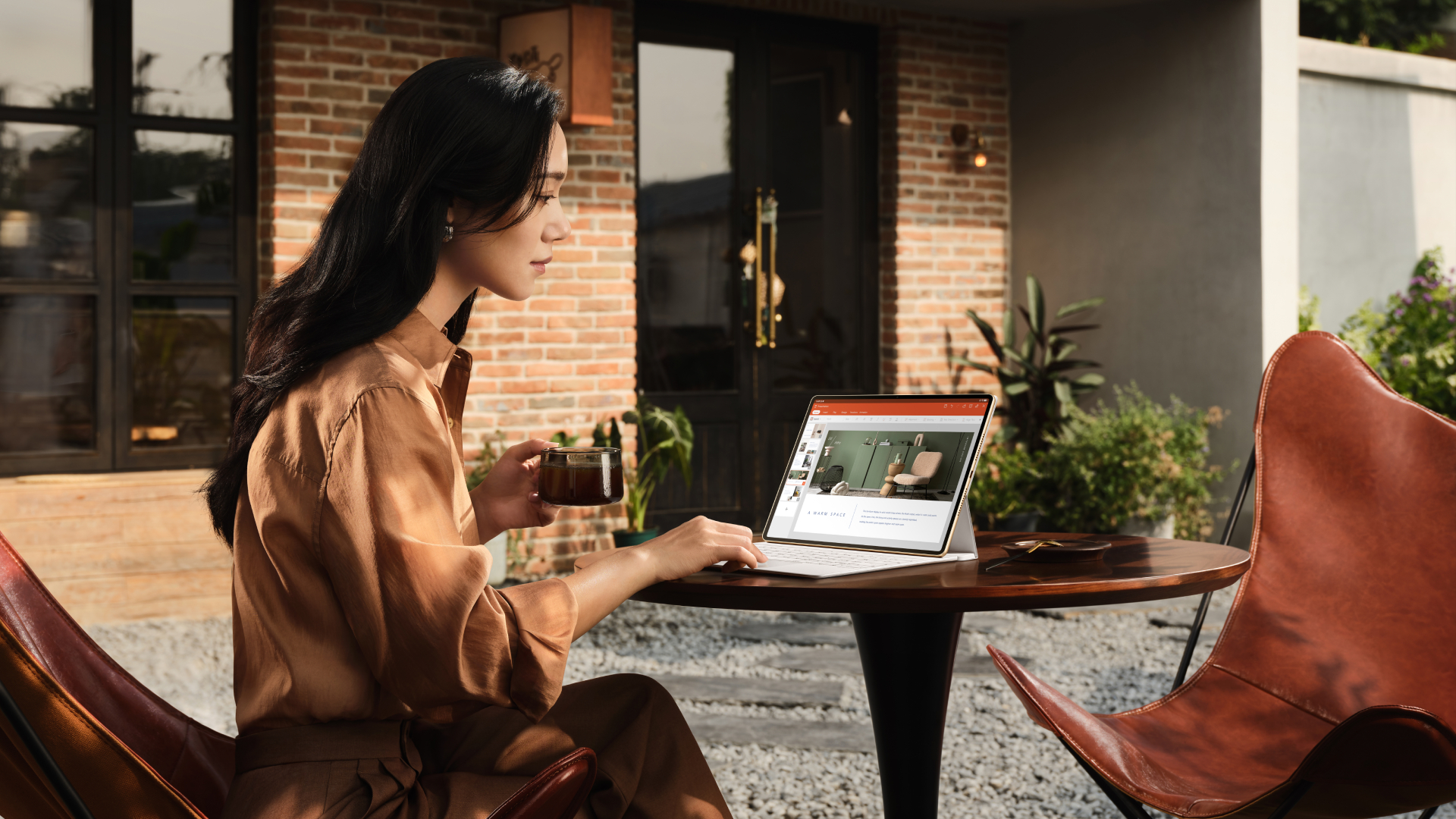 A woman uses a Huawei MatePad pro outdoors, seated at a garden table