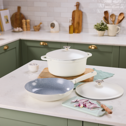 Aldi aluminium frying pan and casserole on a white kitchen island in a kitchen with white countertops and green cupboards.