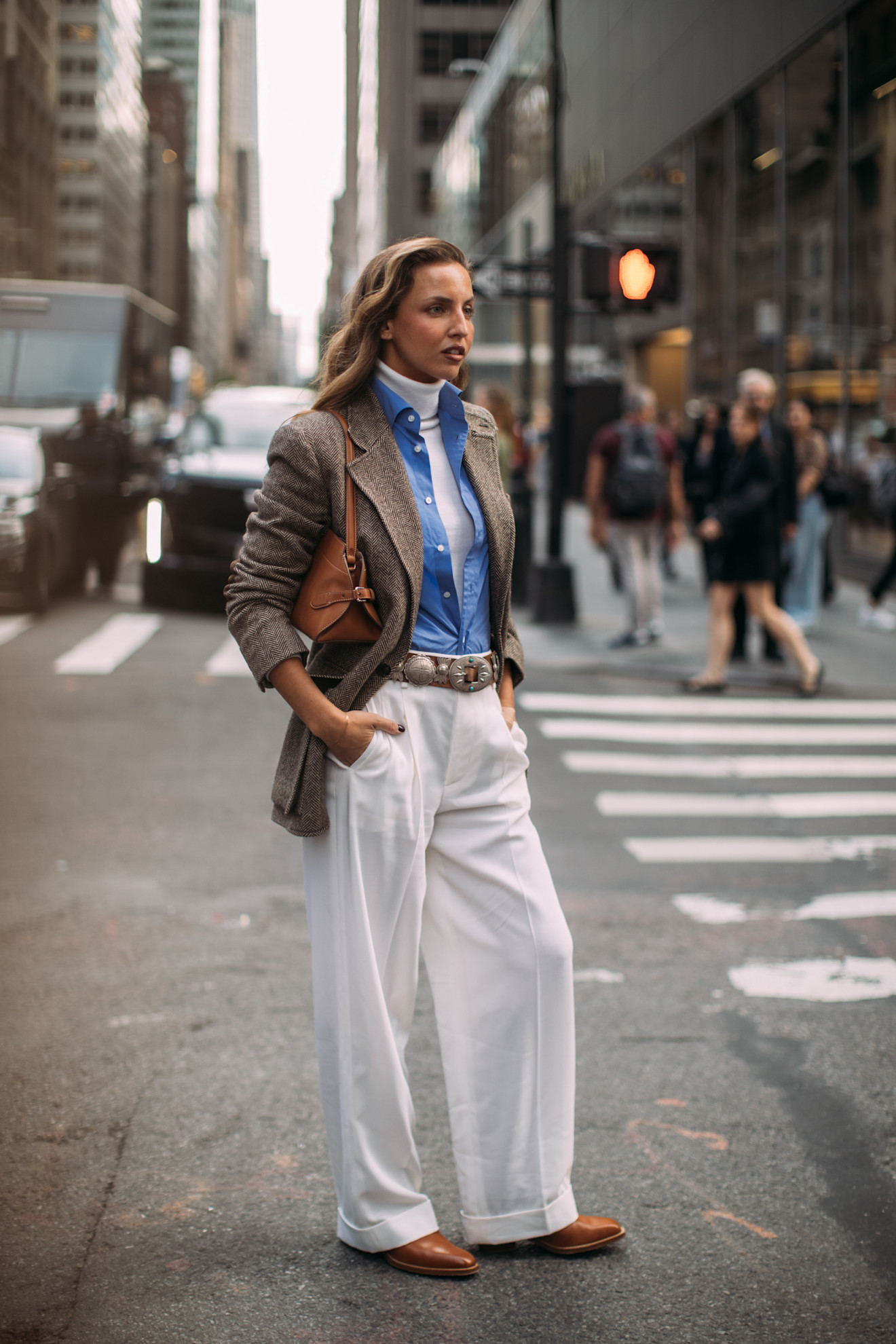 woman wearing white turtleneck, blue button down, white pants, blazer, and purse