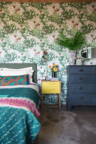 A bedroom with a green printed wallpaper