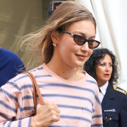 Gigi Hadid styled a striped shirt from Prada with brown corduroy bottoms, black loafers, and a Miu Miu bag at Milan Fashion Week