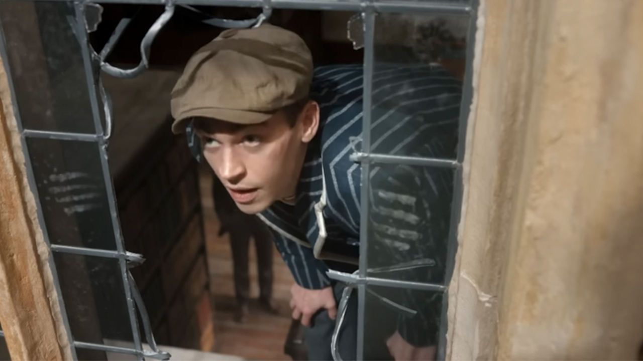 Hero Fiennes Tiffin looking out of a broken window in Young Sherlock Holmes
