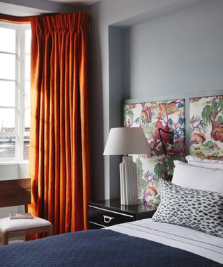 Blue-gray bedroom with floral headboard and orange curtains