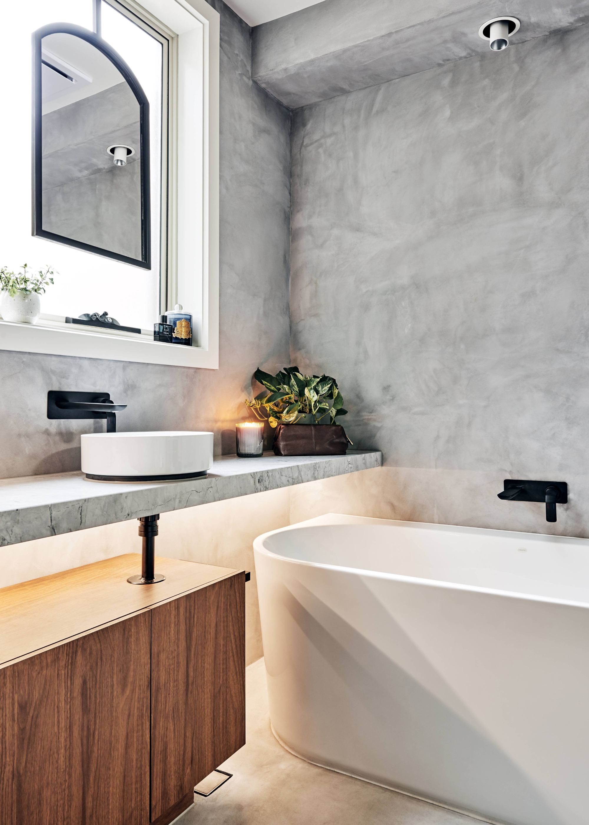 Freestanding bath with microcement walls. In the bathroom is a bathtub and a sink.