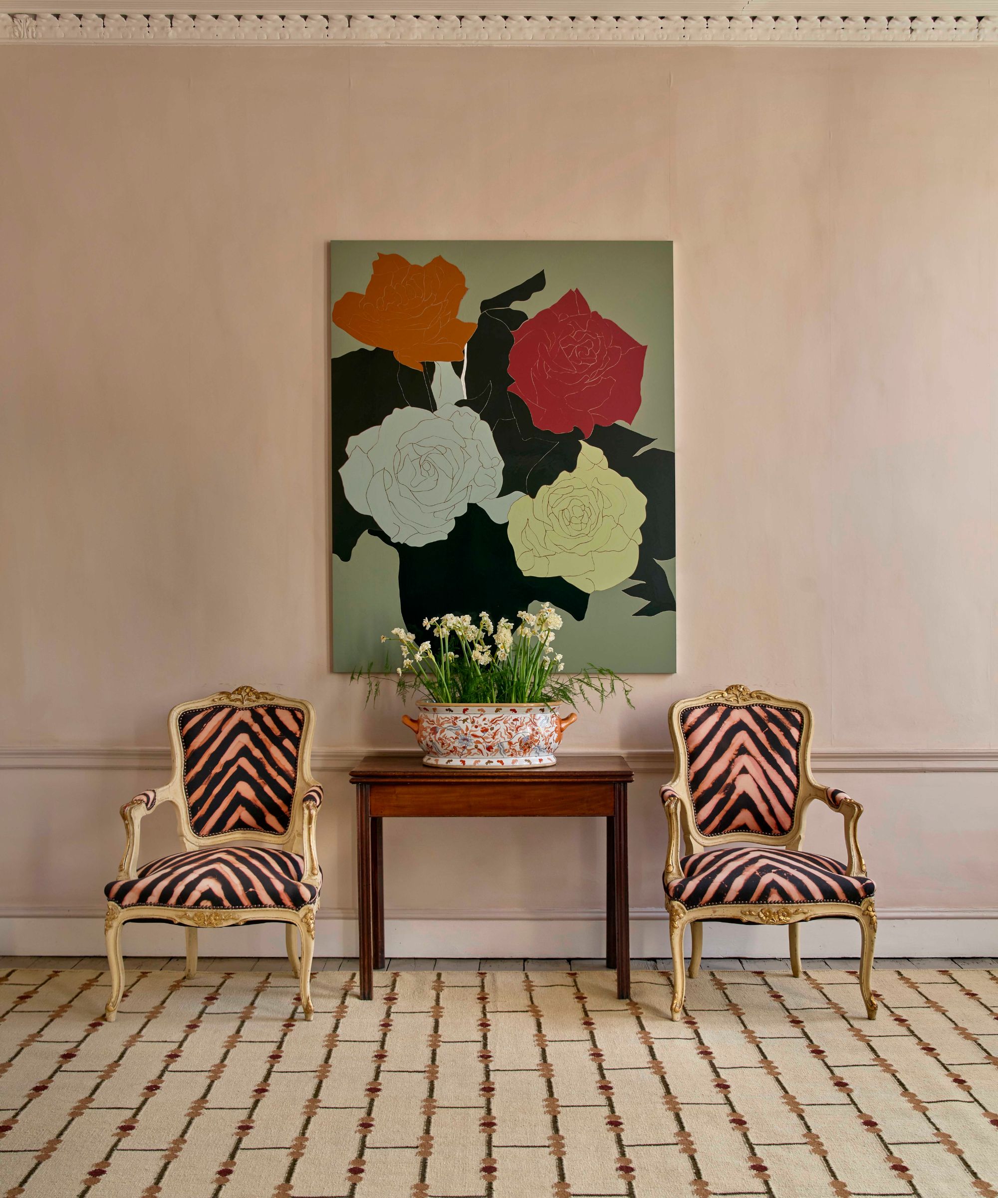 Patterned runner rug extending across a room beneath two armchairs and a console table with artwork above.